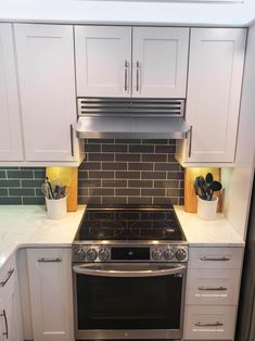 a stove top oven sitting inside of a kitchen next to white cabinets and counter tops