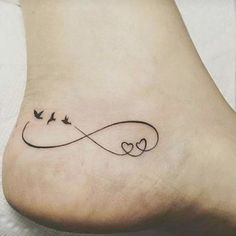 a tattoo on the foot of a woman with two birds flying over an infinite heart