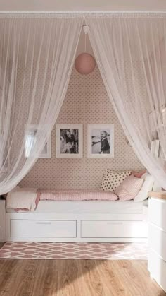 a white bed sitting under a window next to a wooden floor