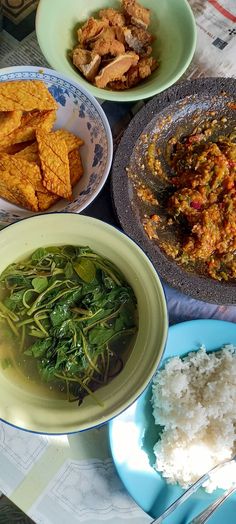 several plates of food on a table with rice and other foods in bowls around them