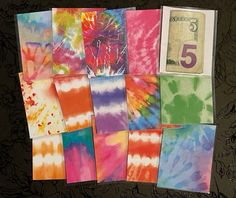 several different colored tie - dyed papers laid out on top of each other with one dollar bill in the middle