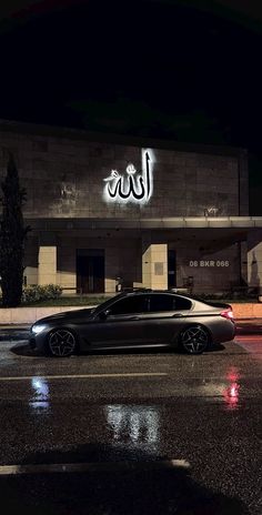 a car parked in front of a building at night with its lights on and arabic writing above it