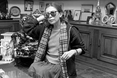 black and white photograph of woman sitting on the floor in front of a table wearing sunglasses