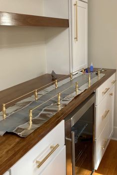 an empty kitchen with white cabinets and wood counter tops that have been wrapped in foil