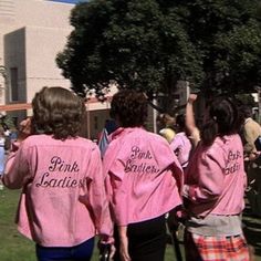 three girls in pink shirts are flying a kite