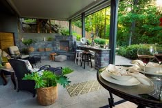 an outdoor kitchen and dining area is shown in this backyard setting with patio furniture, potted plants, and wine glasses on the table