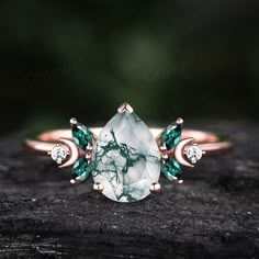 a white and green stone ring sitting on top of a piece of wood with diamonds