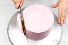 a person cutting a pink cake with a knife