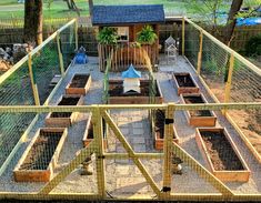 an outdoor garden with lots of plants in the ground and fenced area around it