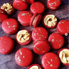 red macaroons with white icing and gold sprinkles on them