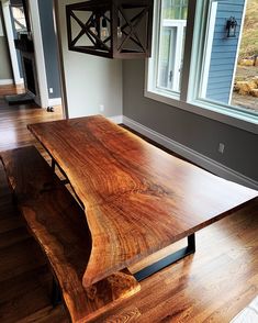 a large wooden table sitting in the middle of a living room next to a window