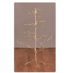 a gold metal tree is standing on a wooden floor