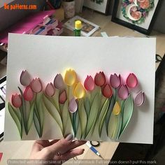 a person holding up a card with flowers cut out of it's paper and glue