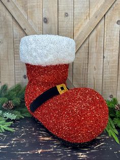 a red and white christmas stocking sitting on top of a wooden table next to pine cones