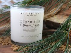 a white candle sitting on top of a wooden table next to pine cones and branches