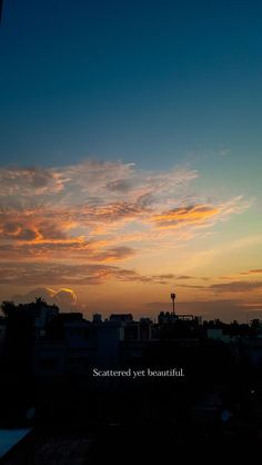 the sun is setting over some buildings with a clock tower in the distance and a sky filled with clouds