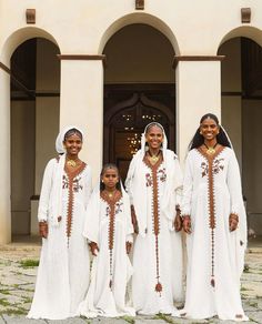 a group of women standing next to each other in front of a building with arches