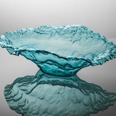 a blue glass bowl sitting on top of a reflective surface with water running down it