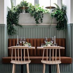 an instagram page with two tables and chairs in front of green walls, plants on the wall