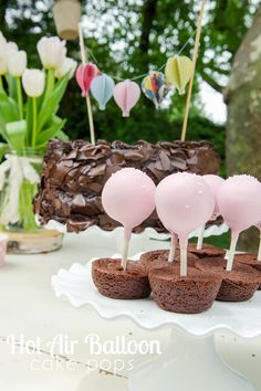 chocolate cake pops with marshmallows are on a white platter next to flowers