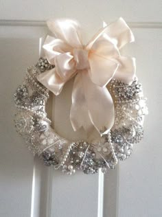 a close up of a wreath on a door with pearls and bows attached to it