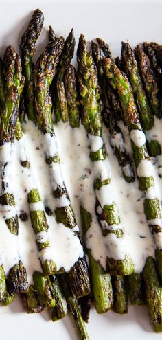 grilled asparagus with ranch dressing on a white platter, ready to be eaten