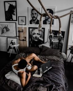 a man laying on top of a bed next to a black and white wall with pictures