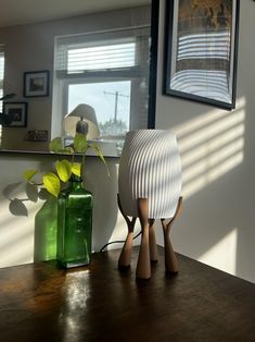 two vases sitting on top of a wooden table next to a green vase with flowers