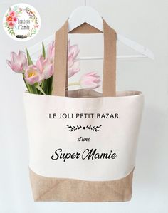 a bag with flowers in it hanging on a hanger next to a sign that says le joli petit bazar