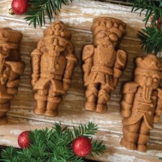 ginger cookies decorated like native american indians on a wooden board surrounded by christmas greenery