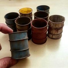 a hand is holding a small stack of tin canisters in different colors and sizes