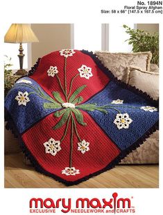 a red, white and blue blanket on top of a couch next to a lamp