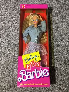 a barbie doll in a pink box on the floor next to a sign that says feeling fun barbie