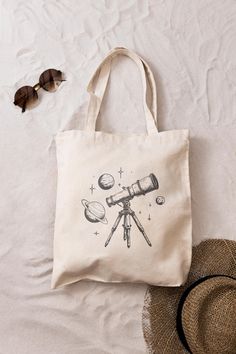 A tote bag for space enthusiasts, featuring designs of telescopes and planets, with a linear and minimalist design. Perfect for daily use, this tote bag is durable and stylish, suitable for carrying essentials around town. Ideal for those who appreciate astronomy and the wonders of the universe. Relevant for gifting on birthdays, holidays, or special occasions. *Made from 100% cotton - made from spun fibers that make a very strong and durable fabric *The tote bag has self-fabric handles with rei Eco Friendly Shopping Bags, Astronomy Gift, Telescopes, Astronomy, Minimalist Design, Bathing Beauties, Eco Friendly, Unique Designs, Electronic Accessories