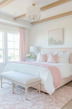 a white bedroom with pink and white decor on the walls, carpeted flooring and large windows