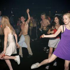 a group of young people dancing at a party with one woman in the foreground