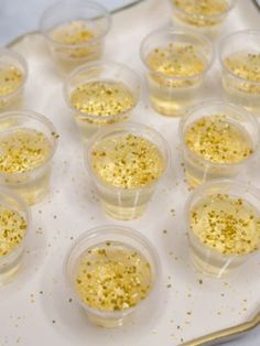 there are many small cups with gold sprinkles in them on a tray