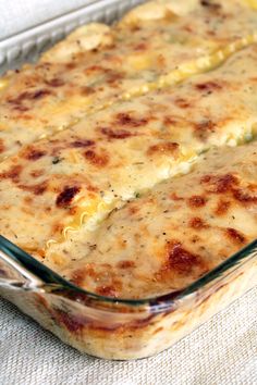 a casserole dish with cheese in it on a white cloth covered tablecloth