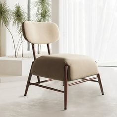 a chair sitting in front of a window next to a potted plant on the floor