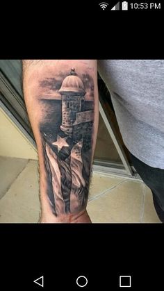 a man's arm with an american flag and lighthouse tattoo on it