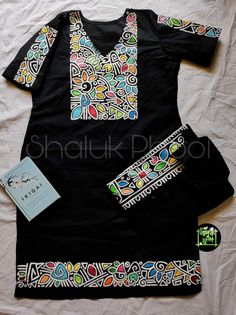 a black shirt with multicolored designs on it and a book next to it