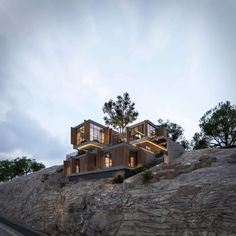 the house is built on top of a rocky hill with trees growing out of it