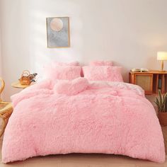 a bed with pink fluffy comforter and pillows