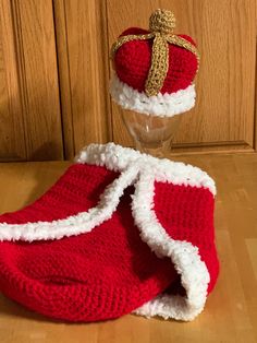 a knitted red and white hat sitting on top of a wooden table next to a glass vase