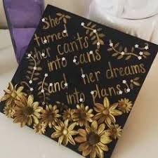 a black graduation cap with gold flowers and words written on the front is sitting on a table