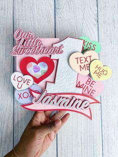 someone holding up a cut out of some type of paper with words and hearts on it