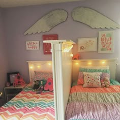 a child's bedroom decorated in pastel colors with angel wings above the bed