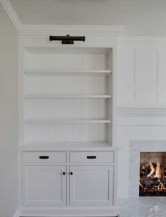 an empty room with a fireplace and built in bookshelves