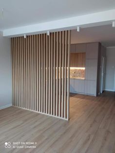 an empty living room with wooden slats on the wall and hard wood flooring