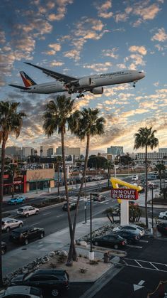 an airplane is flying over a fast food restaurant with palm trees in the foreground